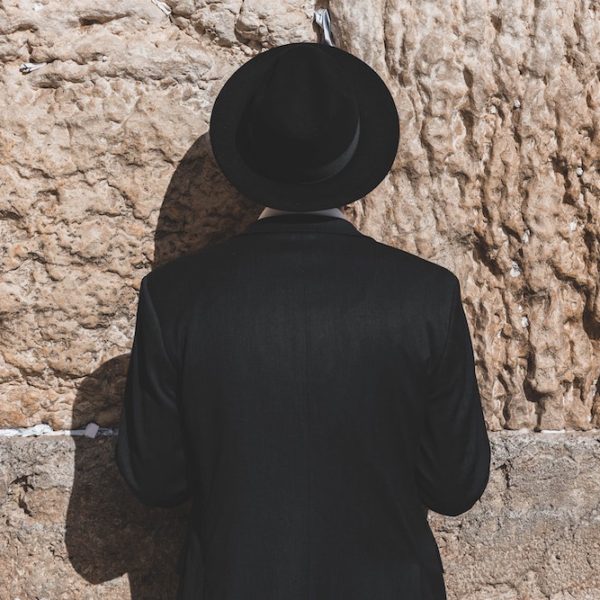 Jewish man dressed in black praying facing the Western Wall