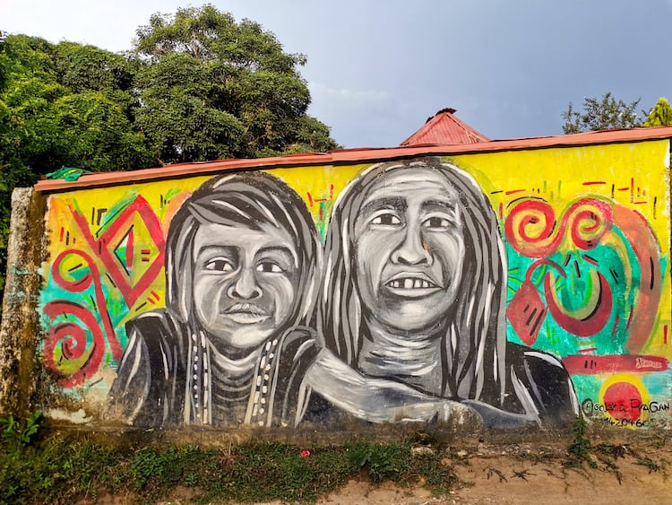 A colourful mural of an indigenous Kogi adult and child on a wall